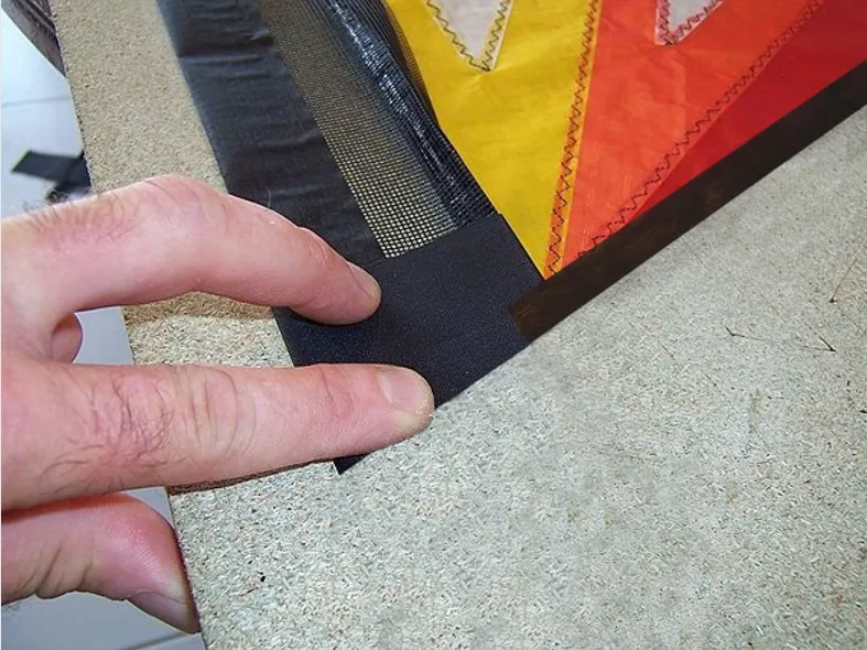 Replier vers l'intérieur de la voile le spi noir de l'ourlet latéral (pour ne pas le couper !) et ensuite couper selon le trait pointillé rouge l'ensemble Dacron/Gaze/Icarex.